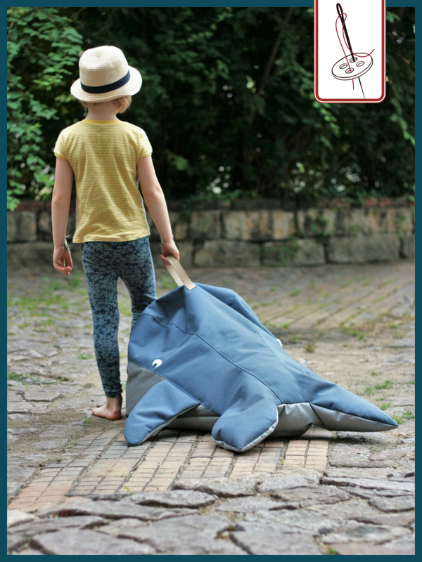 Kind trägt einen Sitzack Wal an der Schlaufe