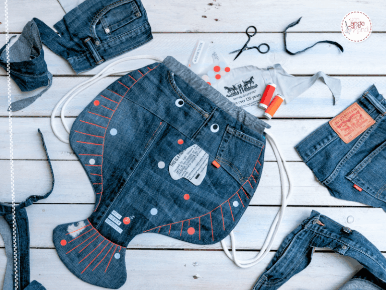 Upcycling-DIY: Selbst genähte Rucksack-Scholle aus Jeans auf weißem Holzuntergrund